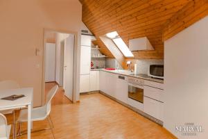 纳沙泰尔Les Galeries Marval的厨房配有白色橱柜和木制天花板