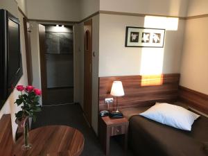 拉多姆格拉斯餐厅酒店的小房间设有一张床和一张带玫瑰花瓶的桌子