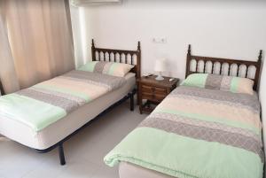 贝尼萨Casa Blanca Suiza的一间卧室设有两张床和床头柜
