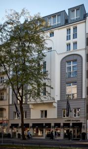 柏林Sir Savigny Hotel, part of Sircle Collection的前面有一棵树的白色大建筑