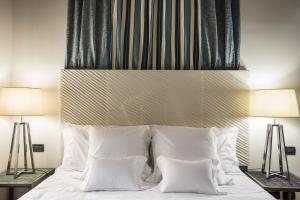 罗马林涅欧别墅酒店的一间卧室配有一张带白色枕头的床和两盏灯。