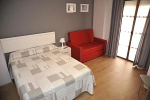 格拉纳达格拉纳达三一公寓式酒店的一间卧室配有一张床和一张红色椅子