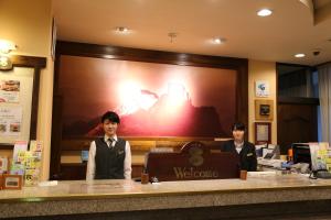 松本新站酒店的两个男人站在酒店大堂柜台后面