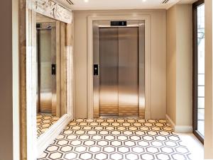 特拉帕尼Hotel San Michele的走廊设有电梯,铺有瓷砖地板