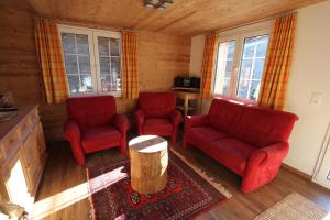 雷金根Chalet Daheim的客厅配有2把红色椅子和桌子