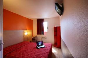 罗尼苏布瓦普瑞米尔罗尼苏博阿经典酒店的配有一张床铺的房间,桌子上摆放着一台笔记本电脑