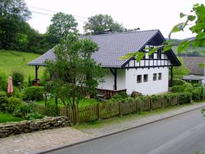 施马伦贝格Ferienwohnung Schmallenberg的白色的房子,有黑色的屋顶和栅栏