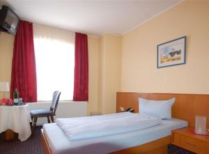 石勒苏益格霍亨索伦酒店的一间卧室配有一张床、一张桌子和一个窗户。