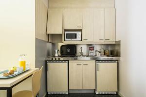 马德里君悦埃拉斯莫旅舍的小厨房配有白色橱柜和微波炉
