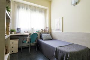 马德里君悦埃拉斯莫旅舍的一间卧室配有一张床、一张书桌和一个窗户。