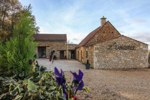 La Chapelle-Aubareil乐维德恩斯住宿加早餐旅馆的一座古老的石头建筑,前面有紫色的鲜花