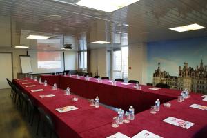 图尔The Originals City, Hôtel La Terrasse, Tours Nord (Inter-Hotel)的一间会议室,配有红色的桌椅和屏幕