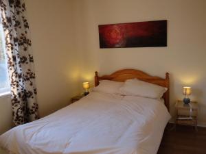 BargrennanCulsharg Cottage的一间卧室配有一张带白色床单和两盏灯的床。