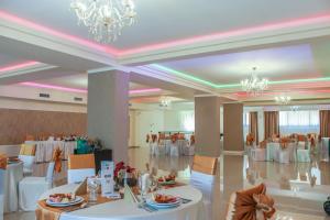 克卢日-纳波卡Hotel Rao的宴会厅配有白色的桌椅和吊灯