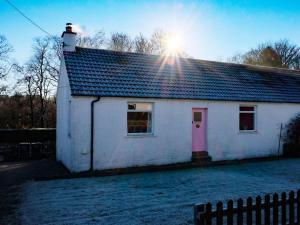 BargrennanCulsharg Cottage的白色的房子,有粉红色的门和太阳