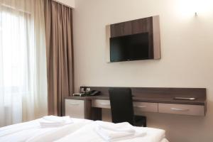 克卢日-纳波卡Hotel Rao的酒店客房设有一张桌子和一台墙上的电视