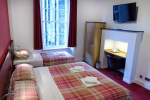 爱丁堡Regent House Hotel - City Centre Hotel的客房设有两张床、一张桌子和一台电视。