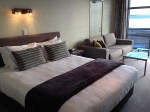 陶波湖帆汽车旅馆的一间卧室配有一张床、一张沙发和一把椅子
