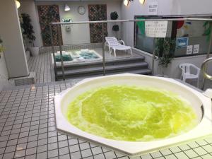 广岛广岛Spa豪华桑拿浴室胶囊旅馆（只限男性）的铺设了瓷砖地板的浴缸里装满了绿色液体