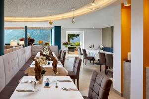 蒂鲁罗Hotel Paradies的餐厅设有白色的桌椅和窗户。