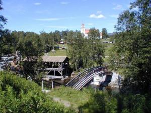 LjusnedalSörmons Stugby的一座桥,在河上,有建筑和树木