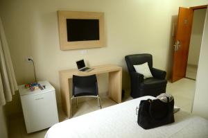 库亚巴卡皮托尔酒店的一间卧室配有一张桌子、一台笔记本电脑和两把椅子