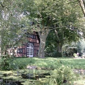 伦格里希明斯特兰德小屋旅馆的一座房子的画,上面有树和池塘