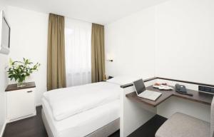 慕尼黑沃尔夫伊甸酒店的酒店客房配有一张床、一张书桌和一台笔记本电脑