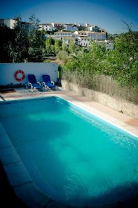 埃尔博斯克Casa del Huerto的一座带两把椅子的蓝色游泳池和一座建筑