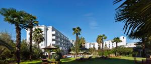 地拉那罗格纳地拉那酒店的一座种植了棕榈树的大型白色建筑,位于公园内