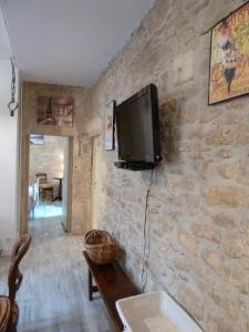 萨尔拉拉卡内达Appartement centre médiéval - Le Cosy de Sarlat的一间客厅,在石墙上配有电视