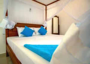 希克杜沃Eden Blue Hikkaduwa的一间卧室配有白色床和蓝色枕头