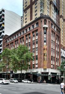 悉尼悉尼胶囊旅馆的城市街道上一座大型砖砌建筑,有汽车