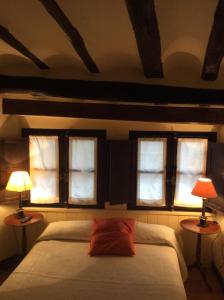 阿尔内迪略Casa Rural Las Pedrolas的一间卧室设有三扇窗户和一张带两盏灯的床。