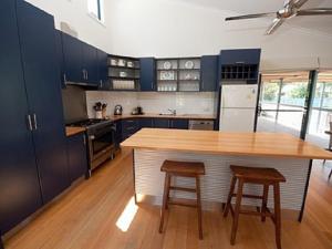 莱克斯恩特伦斯坎布罗度假屋的厨房配有蓝色橱柜、木桌和凳子