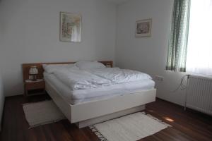 维也纳新城卡萨托颇力诺旅馆的卧室铺有木地板,配有一张白色的床。