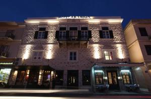 埃尔莫波利斯Hotel Aktaion Syros的一座大型砖砌建筑,晚上有灯