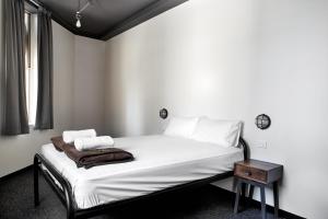 悉尼悉尼胶囊旅馆的一间卧室配有一张带白色床单和一张桌子的床。