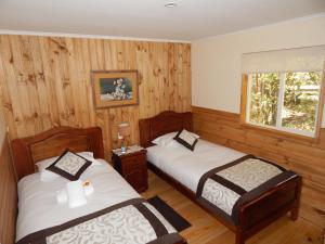 PueloCabañas Nutrias Patagonicas的配有木墙和窗户的客房内的两张床
