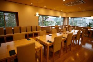 叶山町Shiki Resort Prego Hayama的餐厅设有木桌、椅子和窗户。