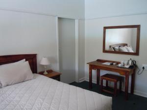 科尔斯伯格Colesberg Lodge的一间卧室配有一张床和一张带镜子的书桌