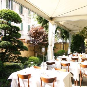 蒙扎第九酒店的一间设有白色桌椅的餐厅,以及一座建筑