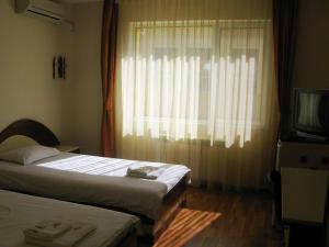 Radnevo纳克拉酒店的一间卧室设有两张床,窗户配有电视。