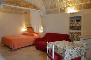 滨海波利尼亚诺La dimora di Poseidone的一间卧室配有一张床、一张红色椅子和一张桌子
