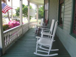 彭萨科拉Pensacola Victorian Bed & Breakfast的门廊上一排挂着美洲国旗的摇椅