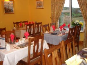 韦斯特波特罗斯莫住宿加早餐旅馆的用餐室配有桌椅和红色鲜花