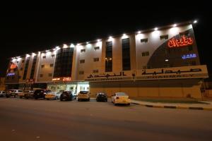 迈季迈阿Raoum Inn Majmaa的一座有汽车在晚上停在停车场的建筑