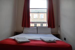 伦敦古德伍德酒店的窗户前的一张床上有两条毛巾
