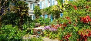 圣瓦斯特拉乌格Hotel de France的一座花园,在一座建筑前方,花园内摆放着桌子和鲜花