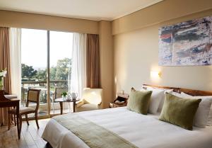 雅典金太阳酒店的配有一张床、一张书桌和一扇窗户的酒店客房